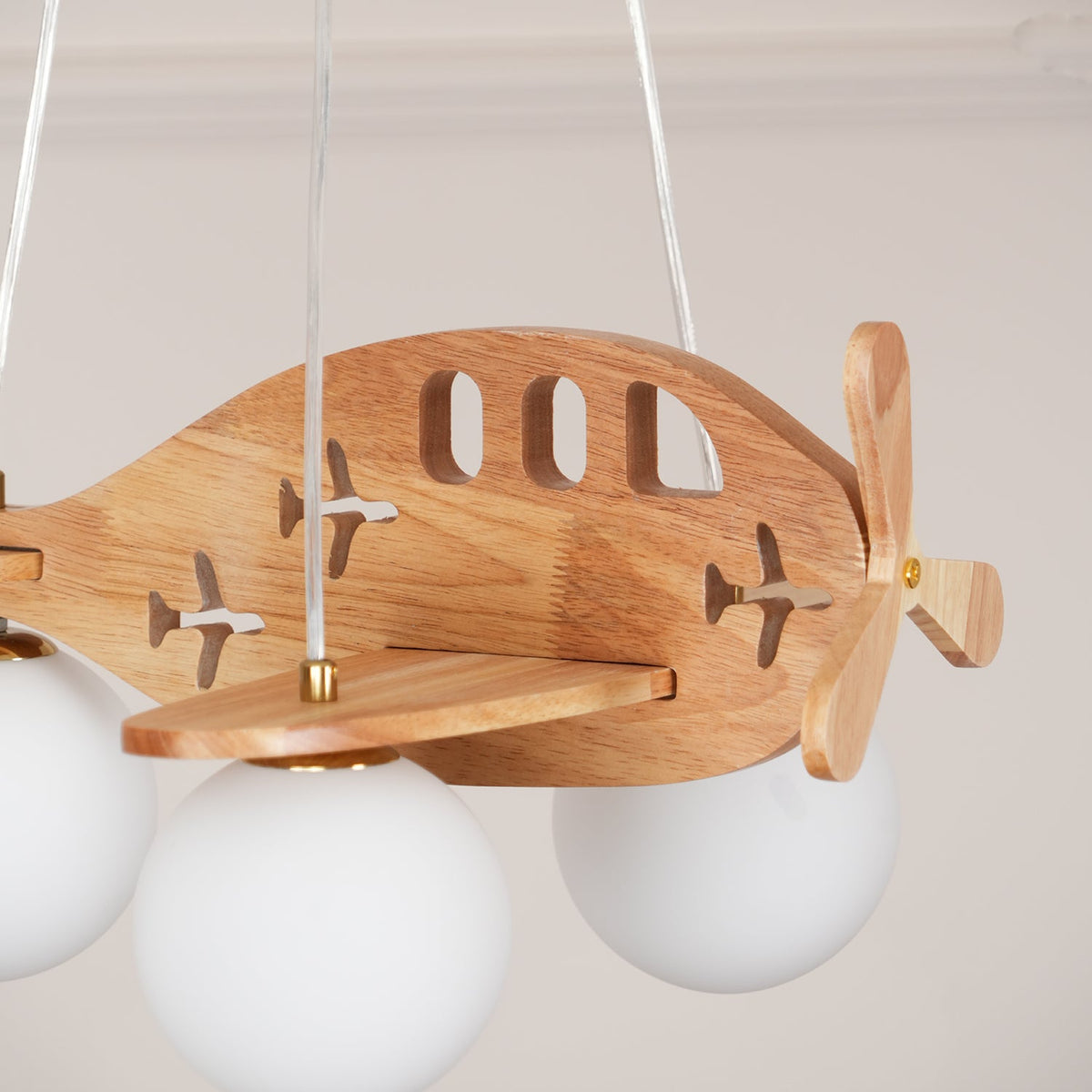 Close view of the arched cut-out windows, small plane shapes and brass pin on the wooden body of this Clérachic airplane light.