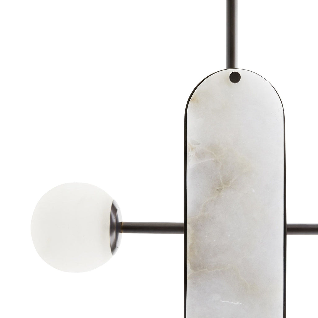 A single stone capsule on the Clérachic Alabaster 5-Light Linear Island Pendant, its amber and grey veining catching the light beside a globe.