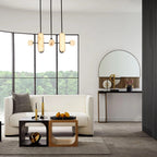 A Clérachic Alabaster 5-Light Linear Island Pendant hanging over a bouclé sofa in a lakeside living room with a curved black-framed window.