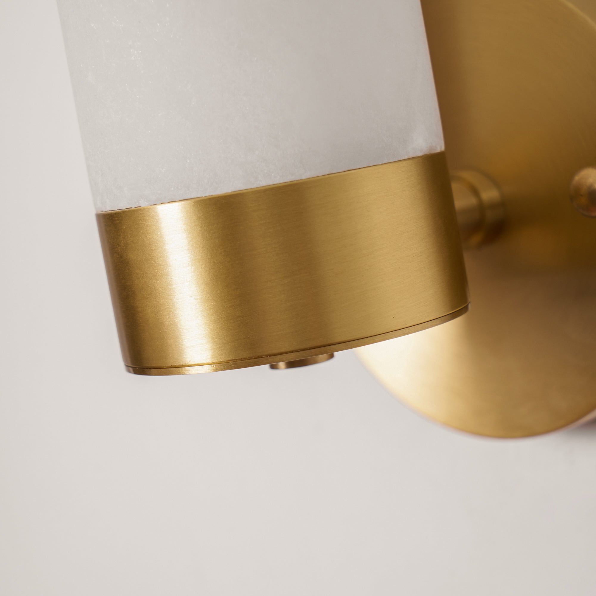 Detail of the Clérachic Alabaster and Brass Wall Sconce where the cut stone shade meets the brushed brass collar.