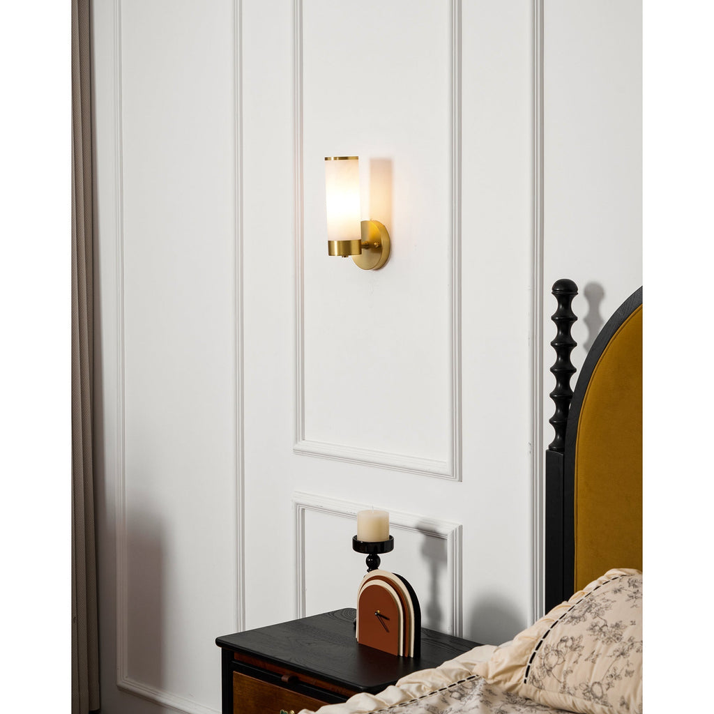 Clérachic Alabaster and Brass Wall Sconce lit as a bedside accent, small enough to sit inside one panel of moulding.