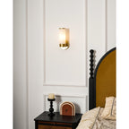 Clérachic Alabaster and Brass Wall Sconce at bedside height, warm light on the wall above a candle and a small clock.