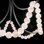 Close-up of the Clérachic Alabaster Bead Chandelier against black, each stone bead lit from within with its veining showing.