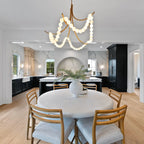 Wide view of the Clérachic Alabaster Bead Chandelier lighting a round dining table set against a marble kitchen beyond.