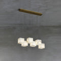 Clérachic alabaster box chandelier, six cube shades hung from a brass bar on concrete.