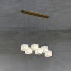 Clérachic alabaster box chandelier, six cube shades hung from a brass bar on concrete.