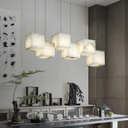 Clérachic box chandelier lit above a sideboard with ferns and a tea set below.