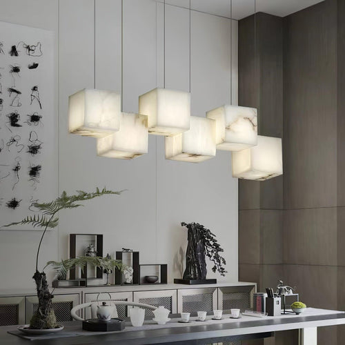 Clérachic box chandelier lit above a sideboard with ferns and a tea set below.