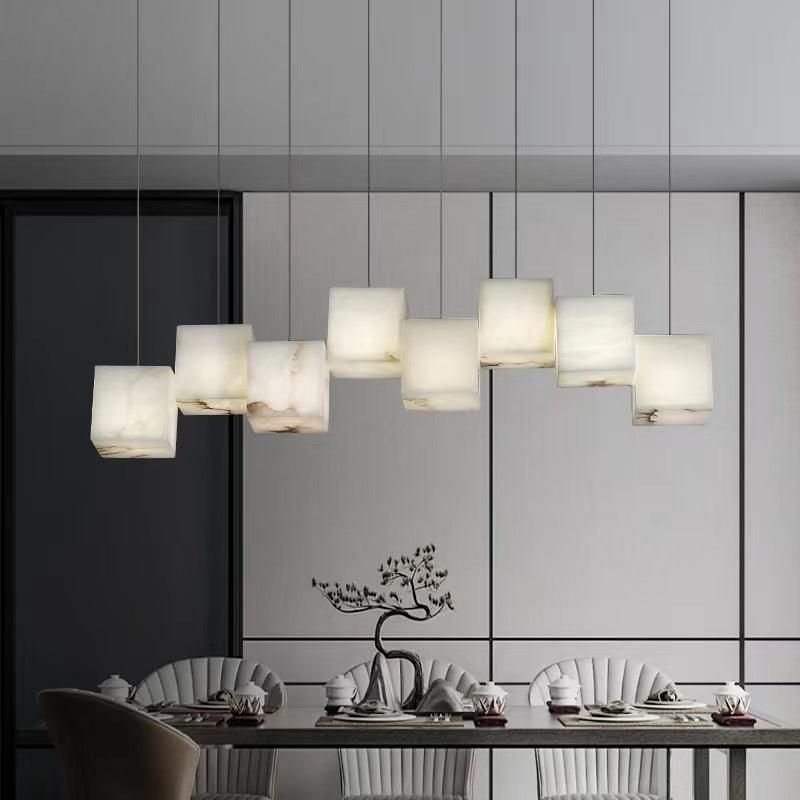 The Clérachic box chandelier lit over a dining table against pale panelled walls.