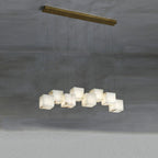 The Clérachic box pendant with ten cubes staggered along a long brass bar on concrete.