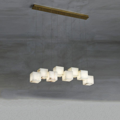 The Clérachic box pendant with ten cubes staggered along a long brass bar on concrete.