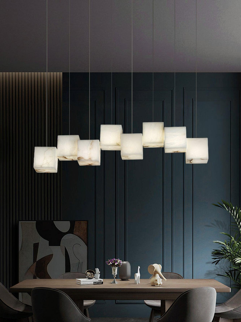 The Clérachic box pendant lit above a walnut dining table against deep teal panelling.