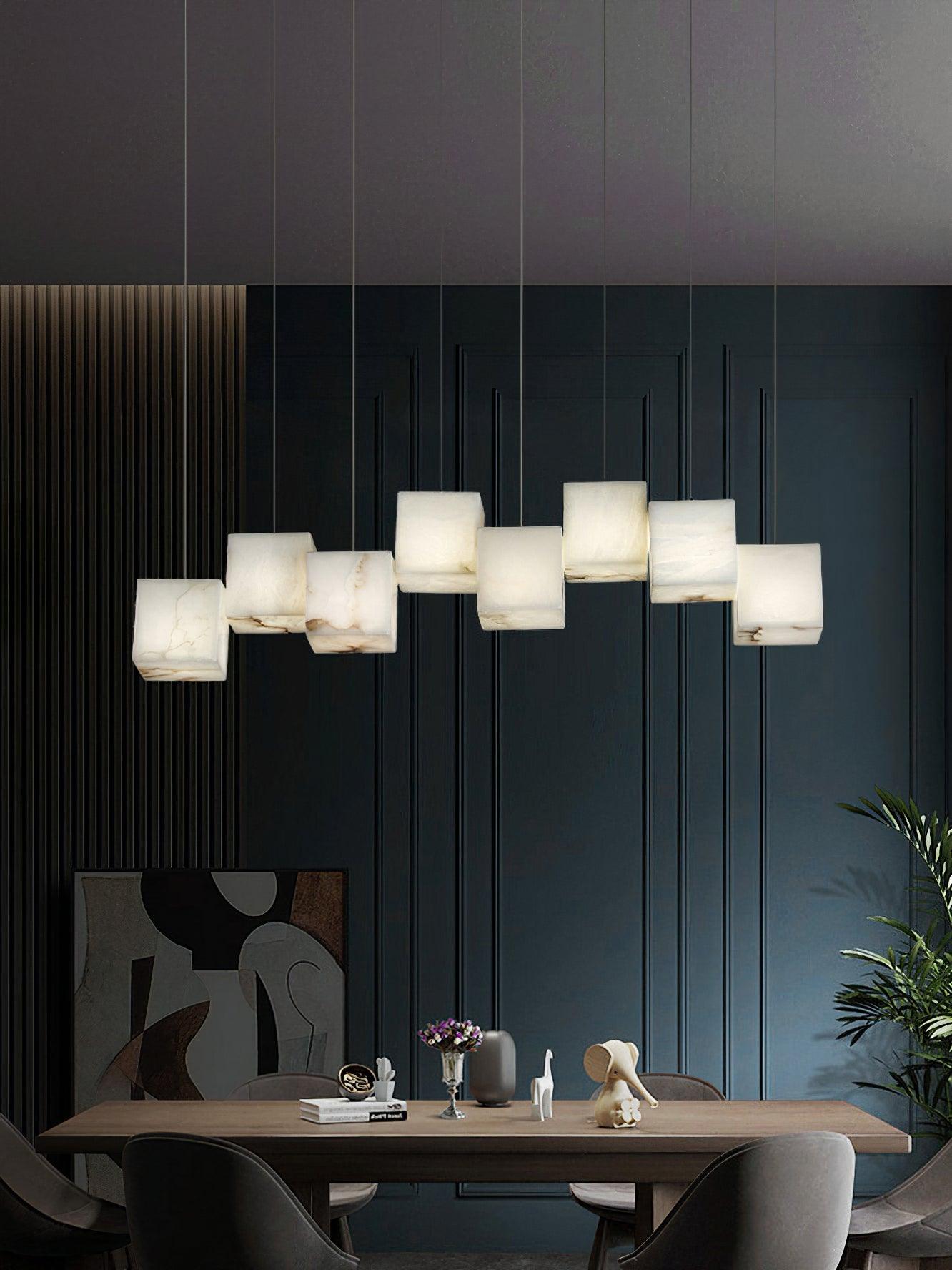The Clérachic box pendant lit above a walnut dining table against deep teal panelling.