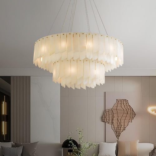 Clérachic cascade chandelier lit above a sofa in a room with a woven wall sculpture.