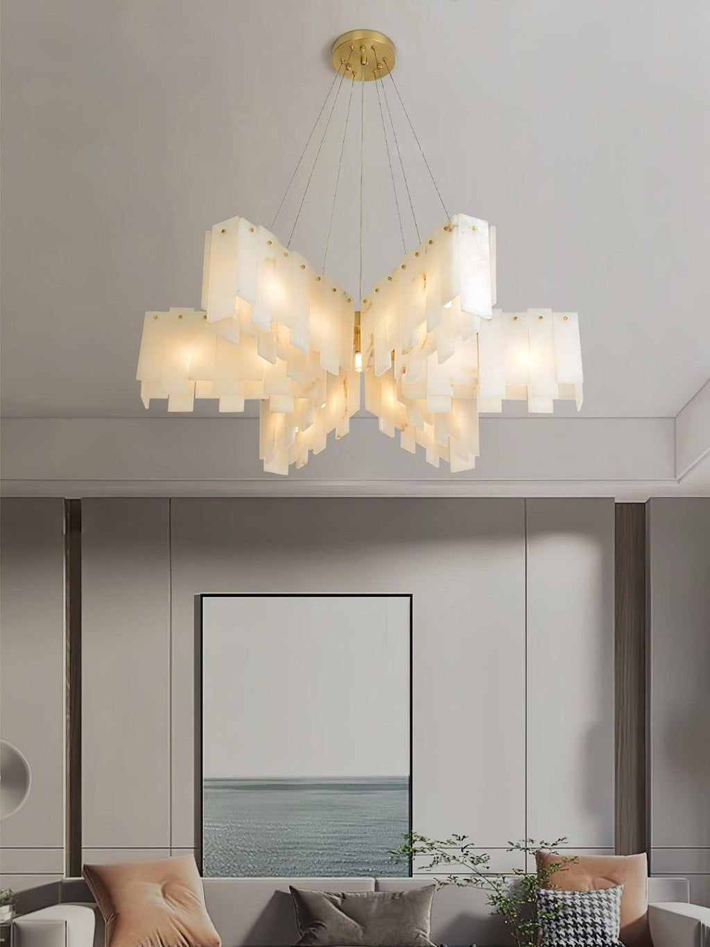 Clérachic cascade chandelier in its widest stepped form, lit above a framed seascape.