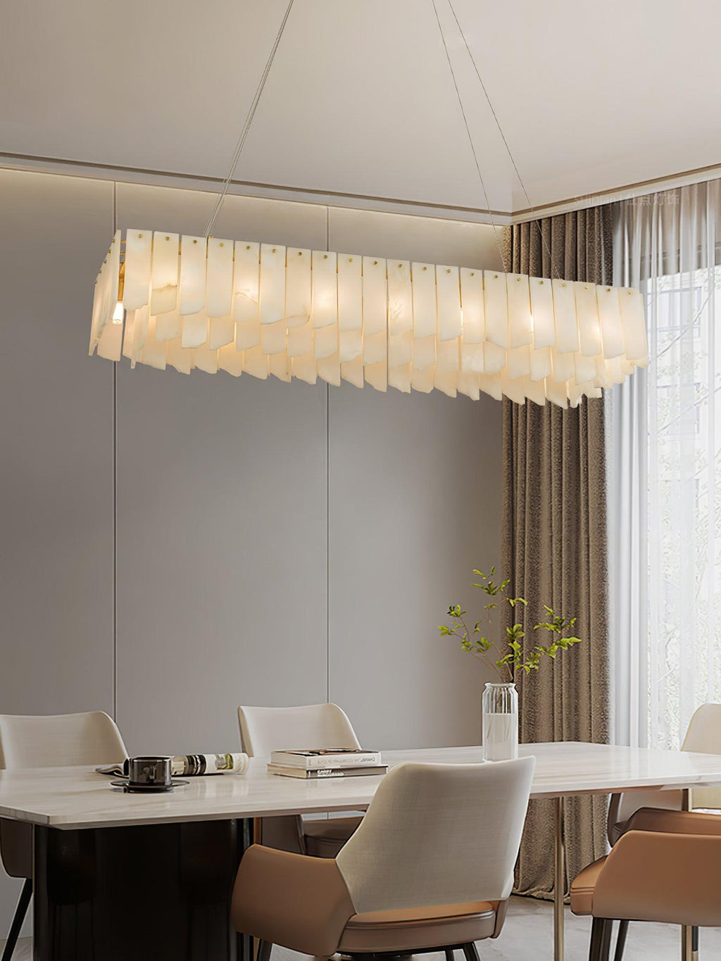 The linear Clérachic cascade lit over a dining table, greenery in a glass vase alongside.