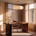 Clérachic round alabaster chandelier hung over a walnut desk with a leather chair, in a sunlit room with linen curtains.