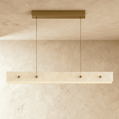Clérachic long alabaster pendant lit softly, its pale veined stone face with four brass studs hanging from a brass ceiling bar.