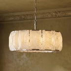 Clérachic alabaster chandelier close up, with lit veined panels, steel clips and a chain below a cornice