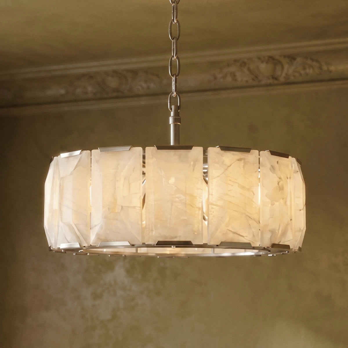 Clérachic alabaster chandelier close up, with lit veined panels, steel clips and a chain below a cornice