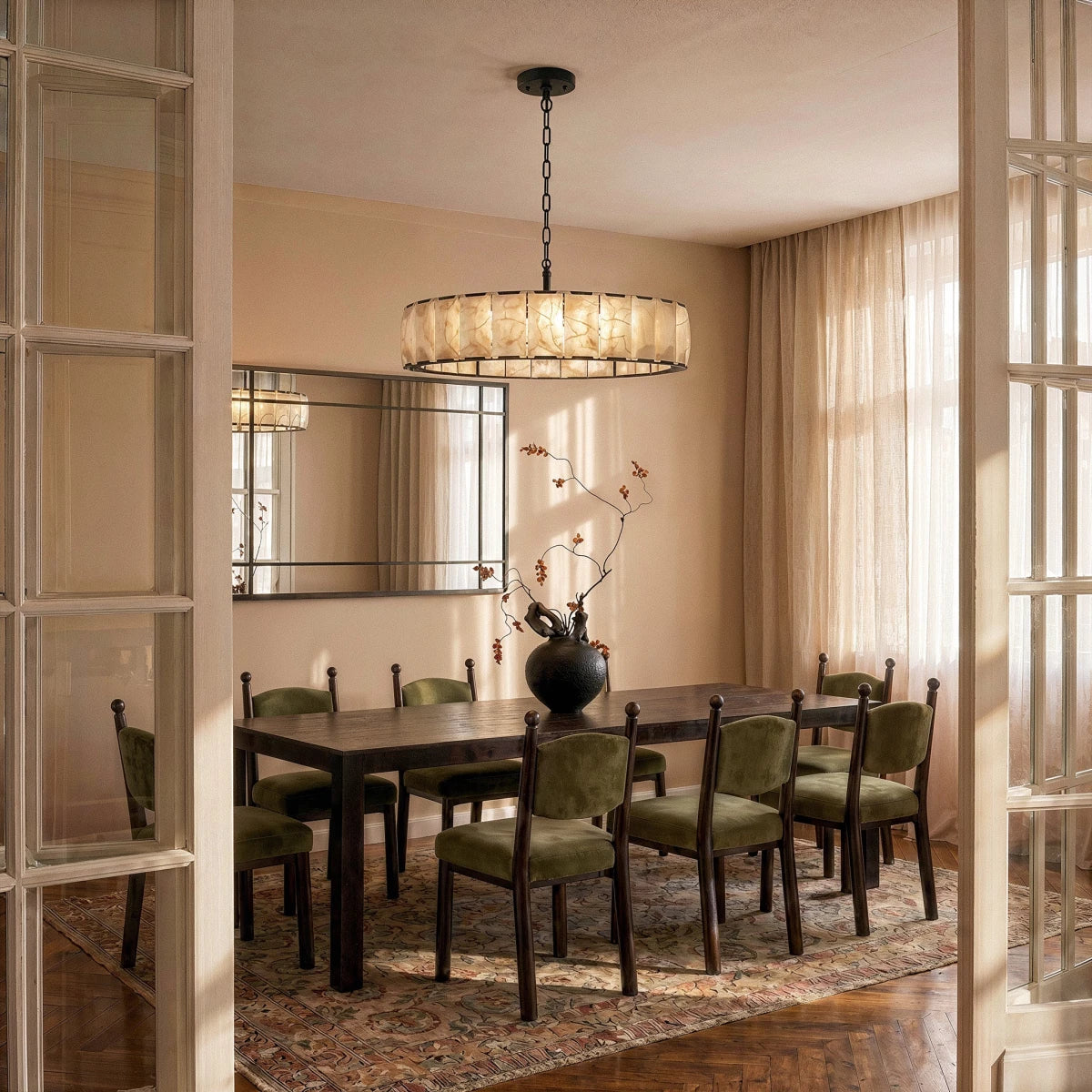 Clérachic wide matte black alabaster chandelier hung over a long dark dining table in a warm dining room