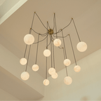 Clérachic spider-style chandelier of lit alabaster-look globes on long cords, hung below a high sloping ceiling.