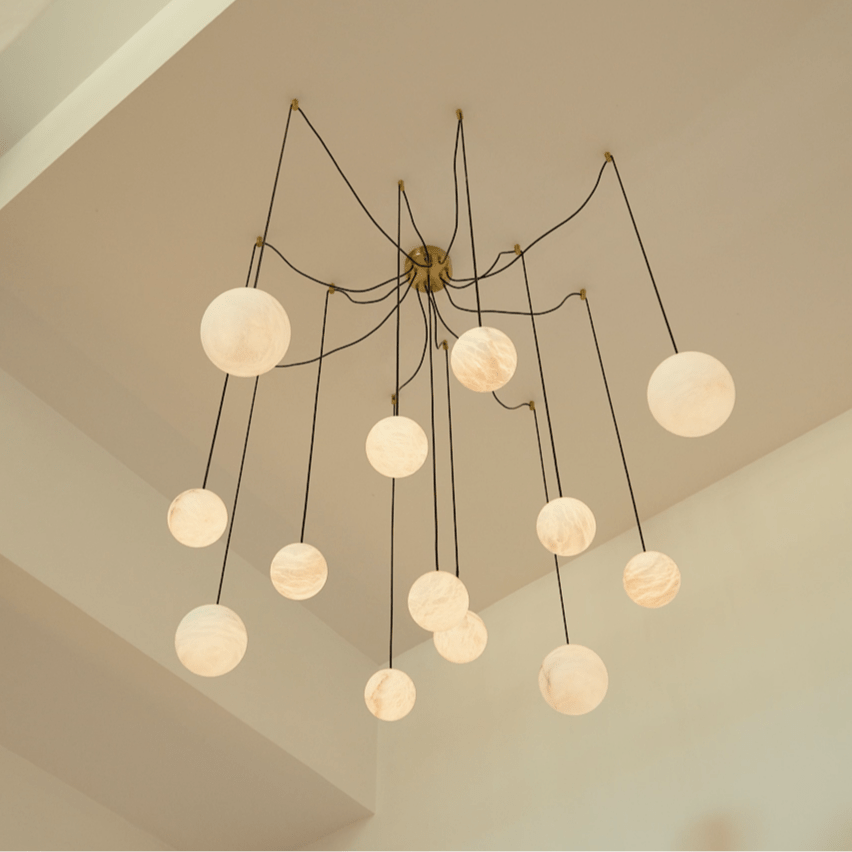Clérachic spider-style chandelier of lit alabaster-look globes on long cords, hung below a high sloping ceiling.