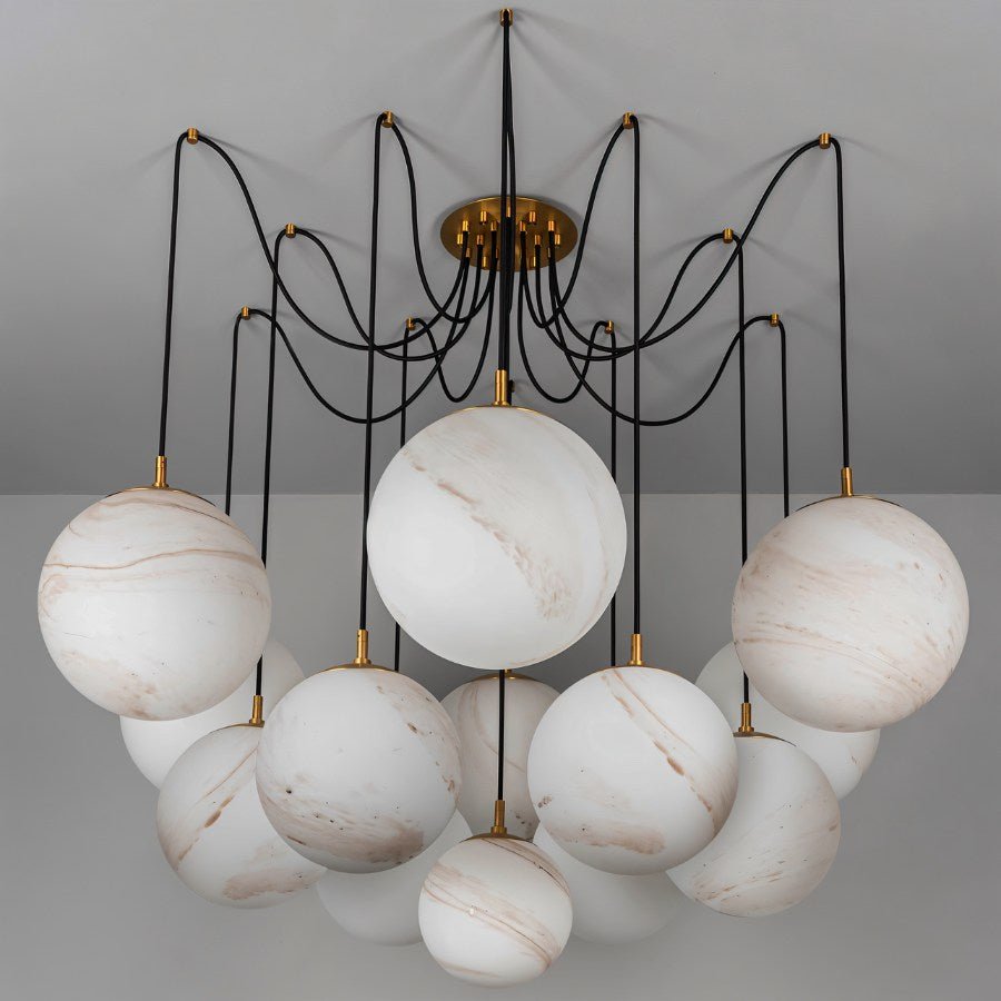 Clérachic chandelier of large veined alabaster-look globes on black cords from a brass canopy, shown unlit against a grey ceiling.