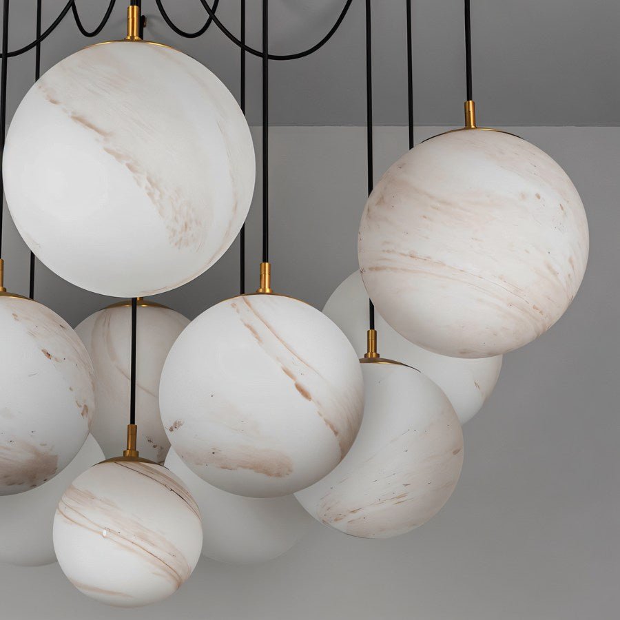 Clérachic close view of large white globes with soft tan veining, hung on black cords with brass fittings, shown unlit.