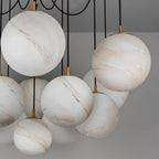 Clérachic close view of large white globes with soft tan veining, hung on black cords with brass fittings, shown unlit.