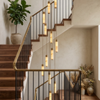 Looking up a switchback staircase, this Clérachic chandelier's brass-capped columns cascade past a potted fig and dried pampas.