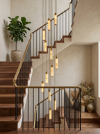 Seen from the foot of the stairs, this Clérachic chandelier's brass-capped columns spiral down past dried pampas grass.