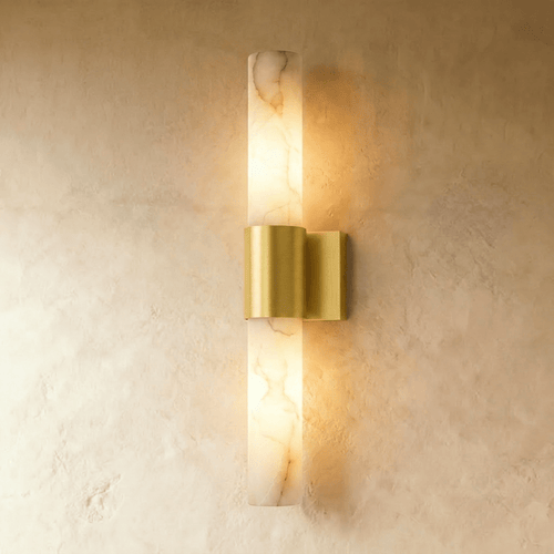 Clérachic 60 cm wall sconce with a veined alabaster column and brushed brass band, glowing warm on a limewash wall.