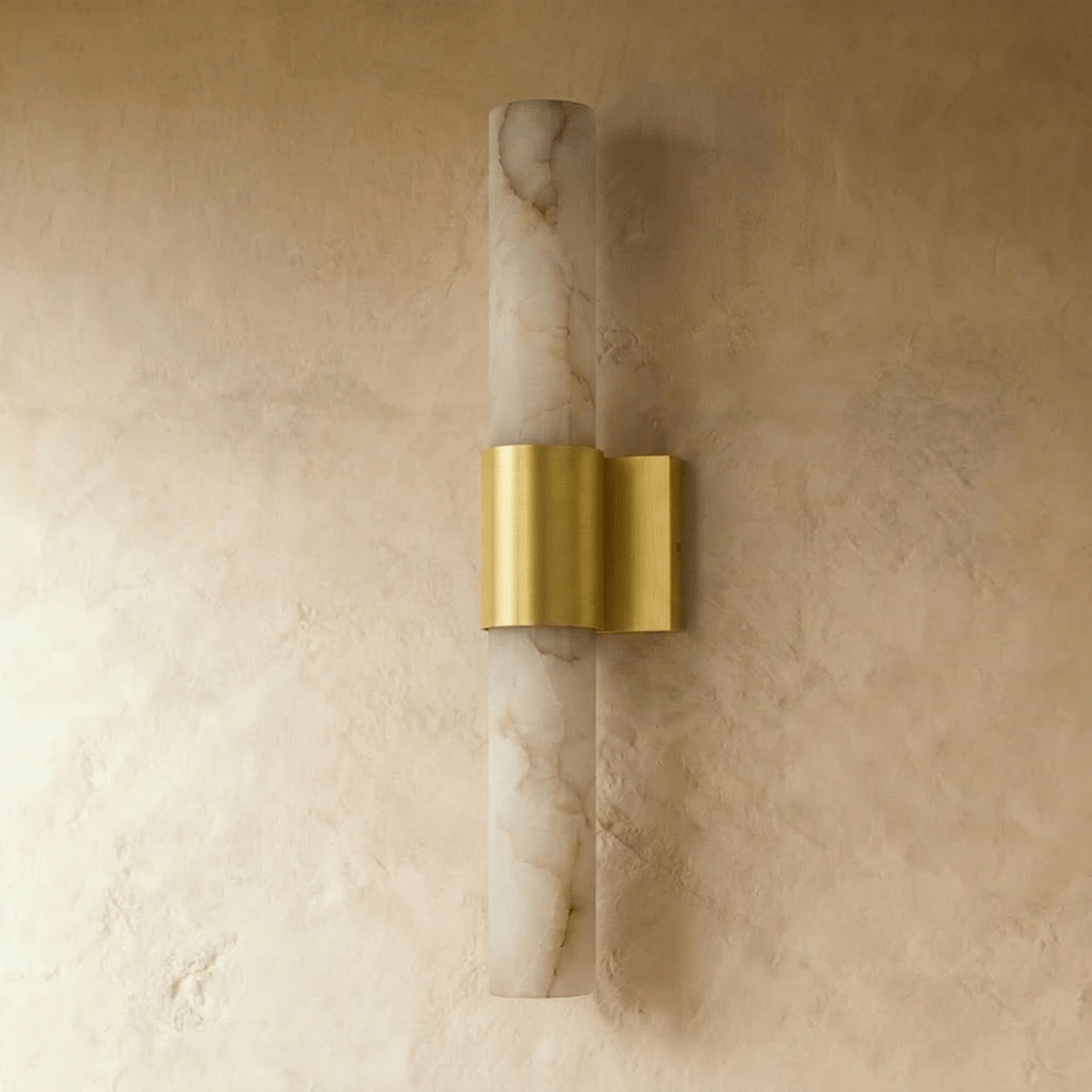 Clérachic wall sconce switched off, its pale veined alabaster column and brushed brass band on a limewash wall.