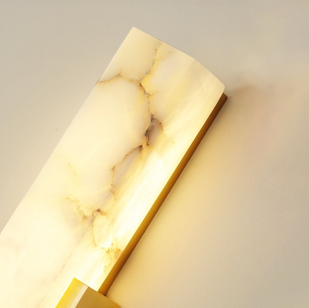 Close view of the white and gold veining in the alabaster bar of this lit Clérachic wall light.