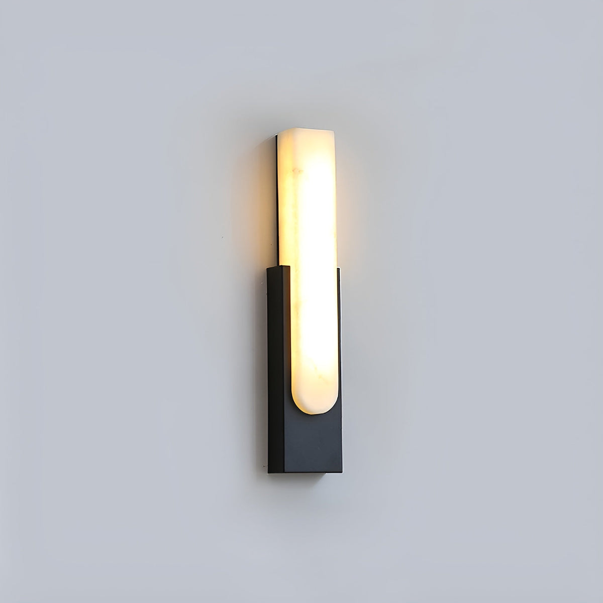Black-backed Clérachic wall light with a glowing alabaster bar, seen against a plain pale grey wall.