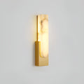 Lit gold-toned Clérachic wall light on a pale grey wall, with strong brown veining running through the alabaster bar.