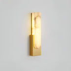 Lit gold-toned Clérachic wall light on a pale grey wall, with strong brown veining running through the alabaster bar.