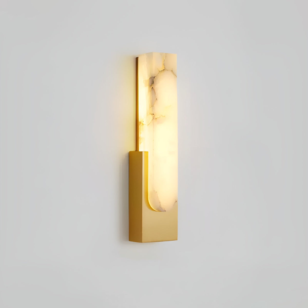 Lit gold-toned Clérachic wall light on a pale grey wall, with strong brown veining running through the alabaster bar.