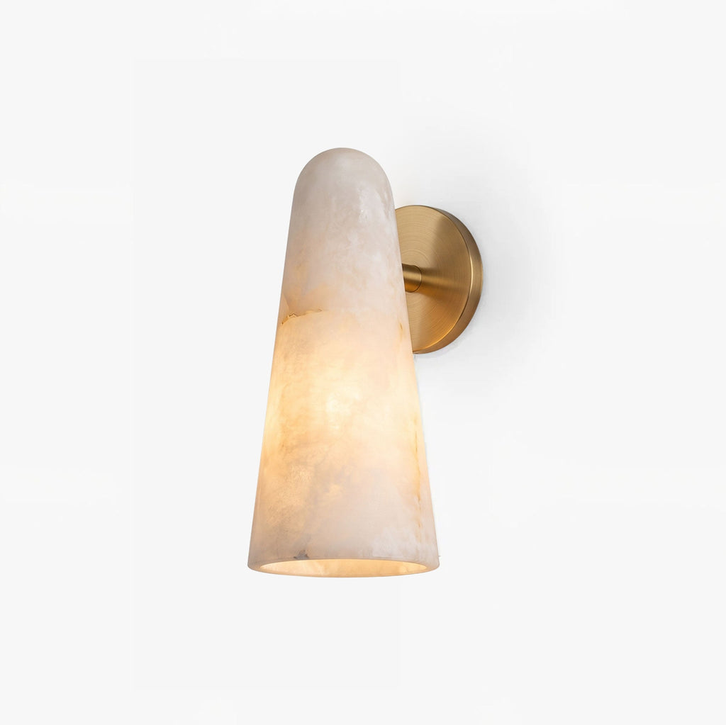 A Clérachic alabaster cone wall light with a brass backplate, glowing warm on a plain white backdrop.
