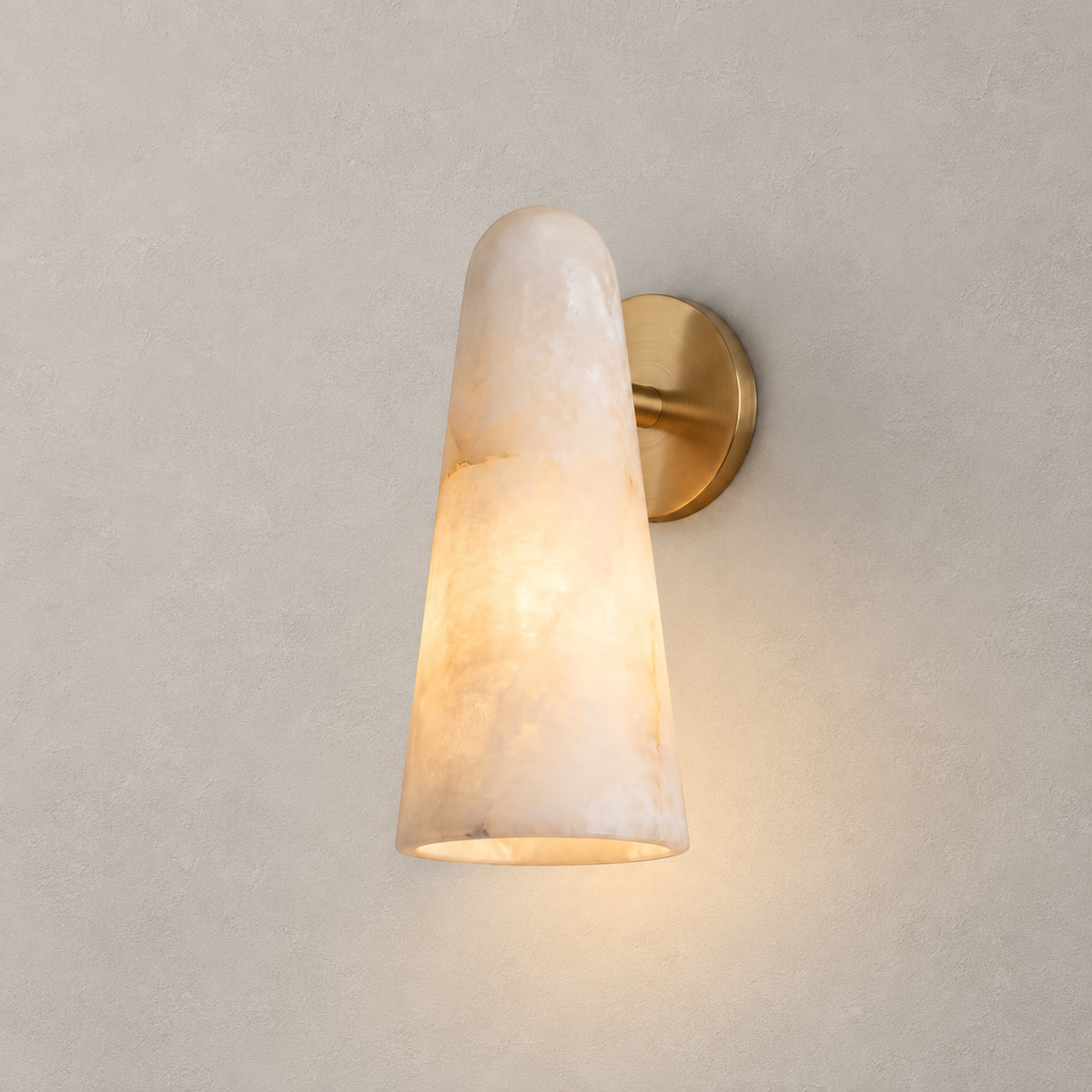 Close view of the veined alabaster cone and round brass backplate of this Clérachic wall light, lit warm against a plain wall.