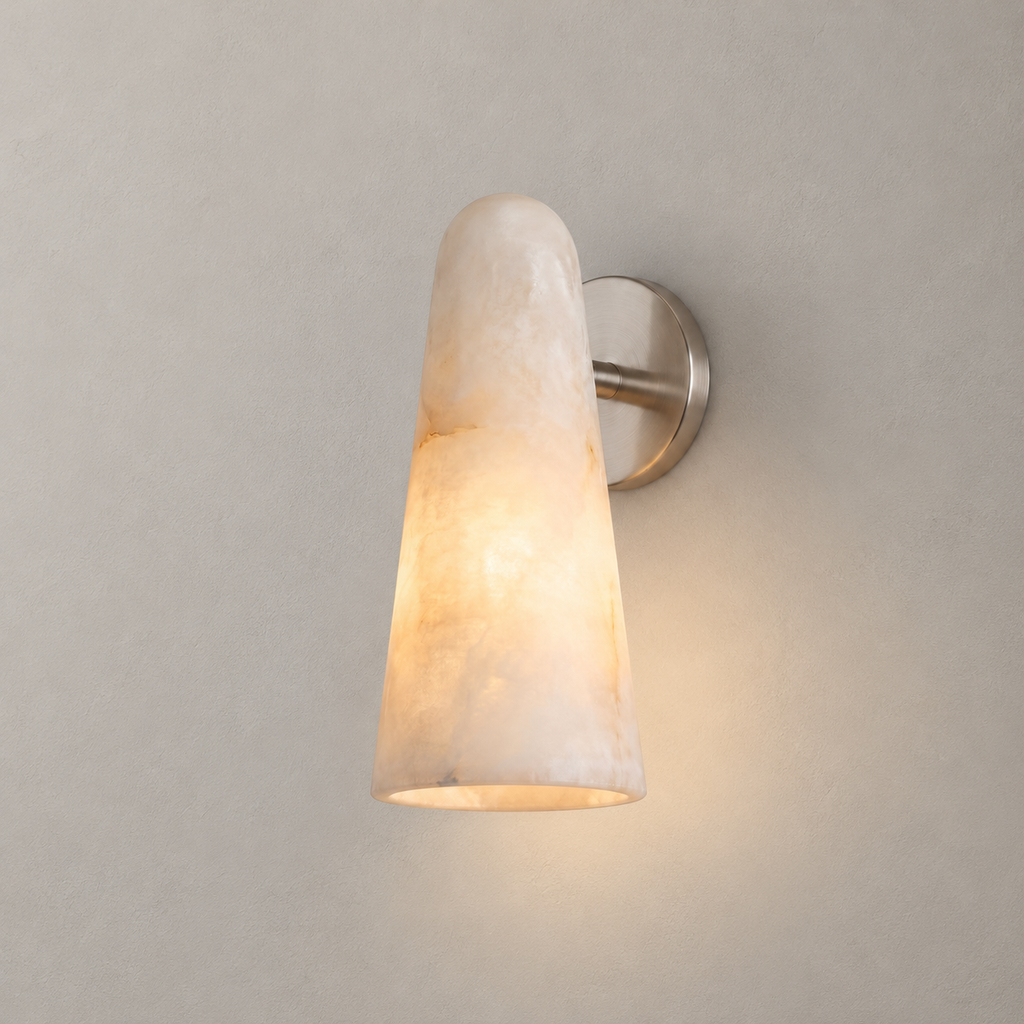 Close view of this Clérachic alabaster wall light with a satin nickel backplate, its white stone shade lit from within.