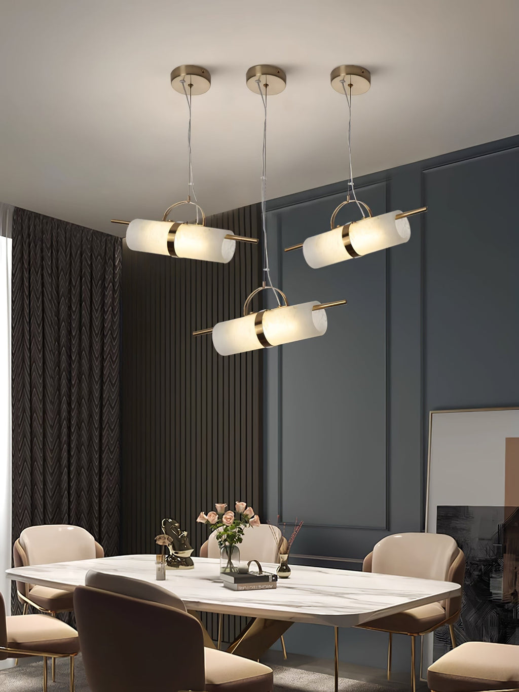 Three Clérachic Alabaster Cylinder LED Pendant Lights staggered above a marble dining table against deep blue panelling.