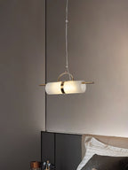 Clérachic Alabaster Cylinder LED Pendant Light hung as a bedside light beside a headboard, warm stone glowing against a taupe wall.