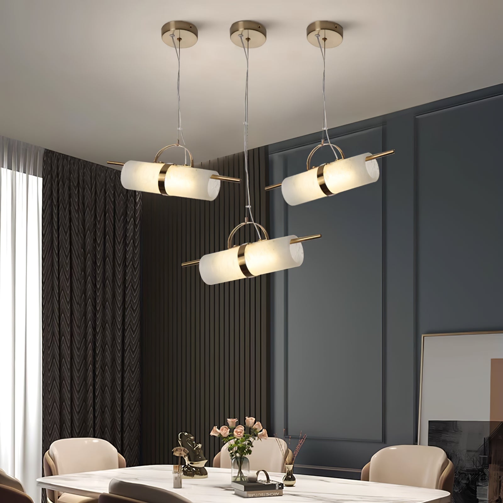 Wider view of three Clérachic Alabaster Cylinder LED Pendant Lights lighting a dining table, each tube warm against the panelled wall.