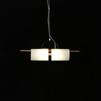 Clérachic Alabaster Cylinder LED Pendant Light seen level against black, warm light filling both halves of the stone tube.