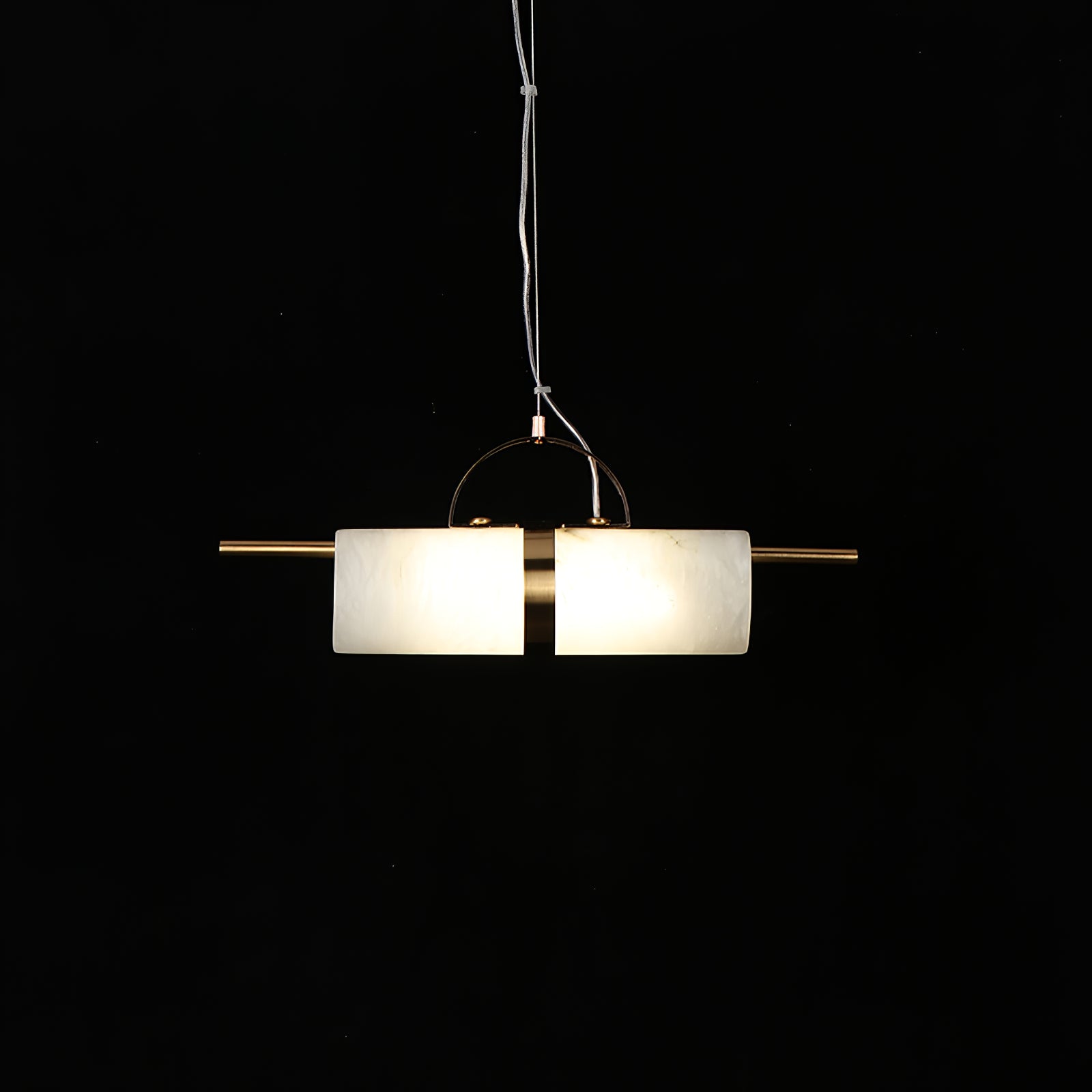 Clérachic Alabaster Cylinder LED Pendant Light seen level against black, warm light filling both halves of the stone tube.