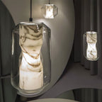 Close view of the clear faceted glass shell and white-veined alabaster core of this Clérachic pendant, lit warm, with a second pendant behind.