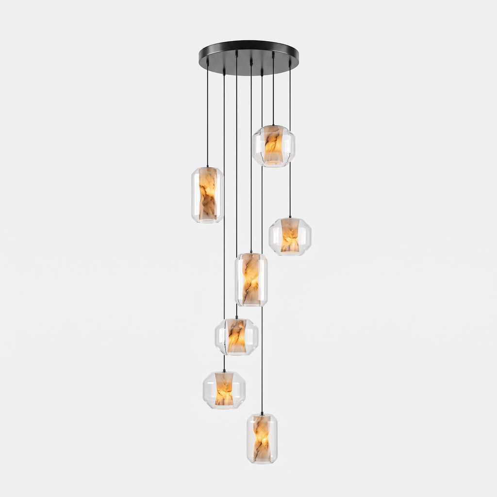 A cluster of seven clear glass Clérachic pendants hangs at staggered heights from a round black canopy on a pale grey backdrop.