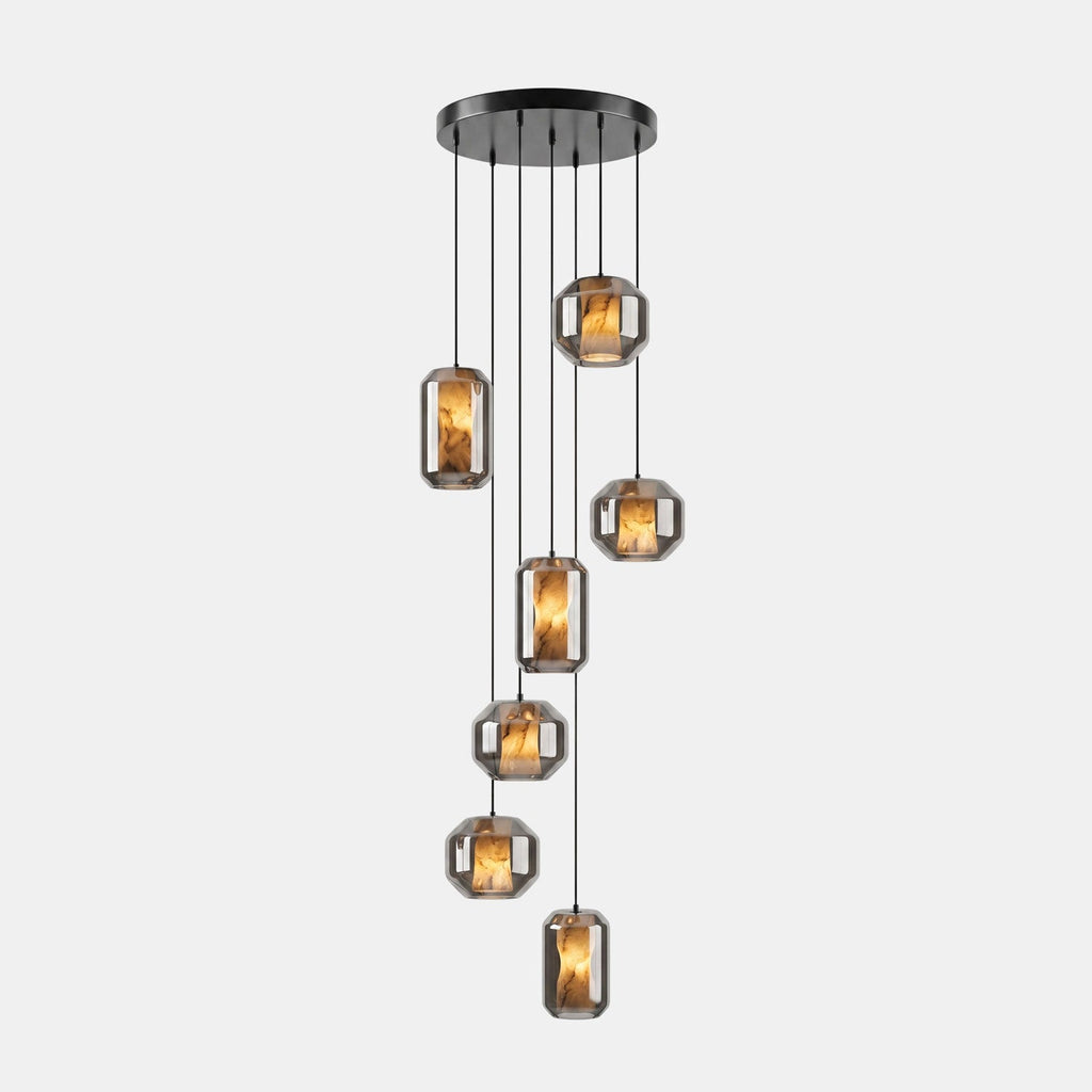 A cluster of seven smoke grey glass Clérachic pendants hangs at staggered heights from a round black canopy on a pale backdrop.